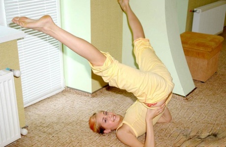 Flexible young girl stretches out on carpeted flooring while fully clothed 80205265
