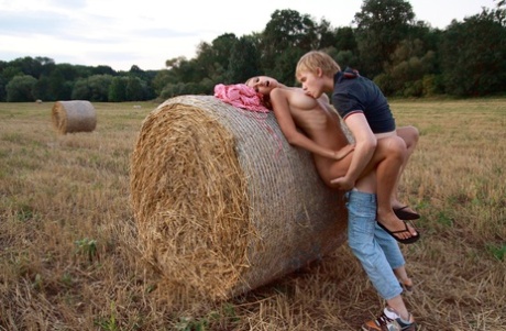 Young couple have sexual intercourse against a round bale in a farmer's field 64863190