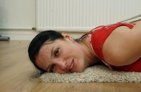 Dark haired female is hogtied in her clothes on a hunk of carpet 23967989