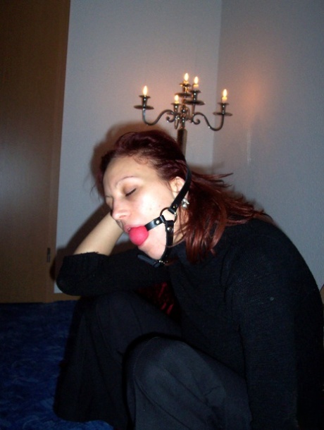 Clothed redhead affixes a ball gag while sitting afore a St Andrew's Cross 38482304